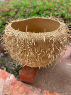 a vase made out of straw sitting on top of a brick wall