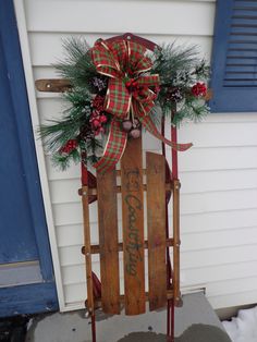 a wooden sled decorated with pine branches and red berries is sitting on the front porch