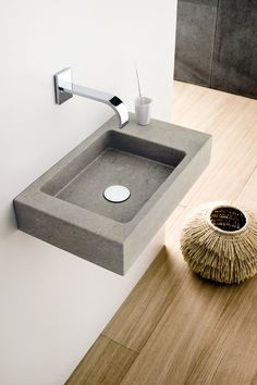 a bathroom sink sitting on top of a wooden floor next to a wall mounted faucet