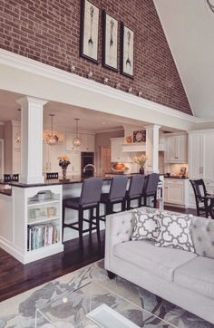 a living room filled with furniture next to a kitchen and dining room table in front of a brick wall