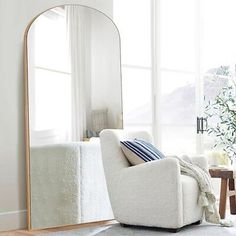 a living room filled with furniture and a large mirror on the wall next to a window