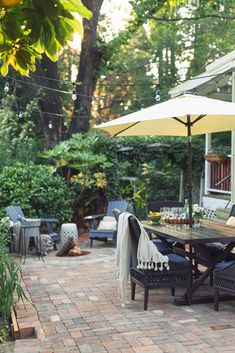 an outdoor dining area with patio furniture and umbrellas on brick paversed walkway