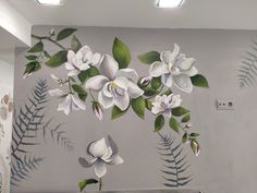 a painting of white flowers and green leaves on a gray wall