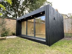 a black building sitting in the middle of a yard