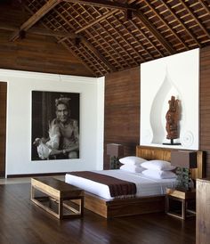 a bedroom with wood flooring and white walls has a large painting on the wall