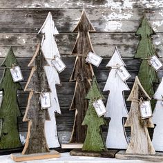 wooden christmas trees with tags on them are displayed in front of a weathered wood wall