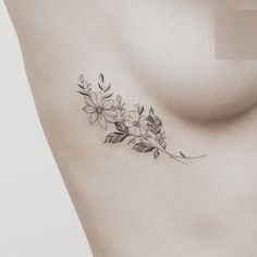 a woman's chest with flowers and leaves tattooed on the left side of her stomach