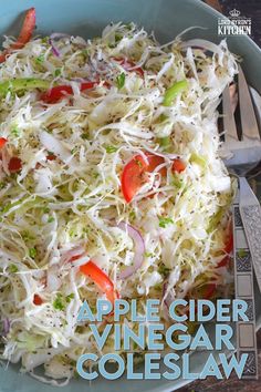 a bowl filled with coleslaw and tomatoes on top of a wooden table next to a fork