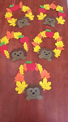 the fall wreaths are made out of paper and have leaves, apples, and bears on them