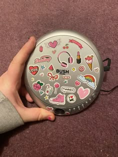 a person holding onto a silver object with lots of stickers on it