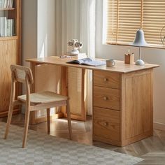 a wooden desk with a chair next to it in front of a book shelf and window