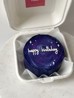 a birthday cupcake in a white box with purple frosting that says happy birthday