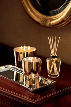 three candles are sitting on a table next to some glass containers with reeds in them