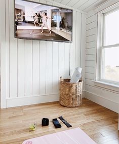 a flat screen tv sitting on top of a wooden floor next to a basket filled with cell phones