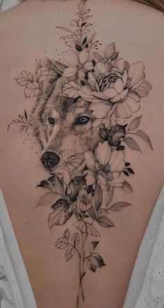 a woman's back with a wolf and flowers on it