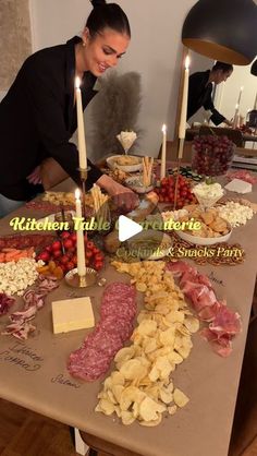 a woman sitting at a table filled with food and candles in front of her face