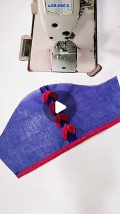 the sewing machine is next to an object that looks like a piece of cloth with red and blue ribbons on it