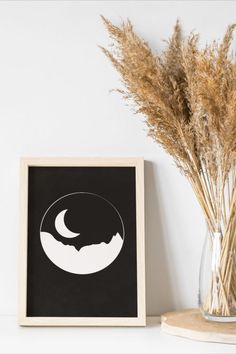 a black and white photo sitting on top of a shelf next to a vase filled with dry grass