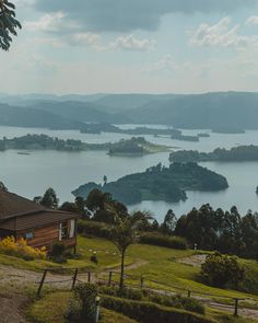 a house sits on top of a hill overlooking a lake and mountains in the distance