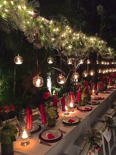 a long table is set with candles, plates and place settings for an outdoor dinner