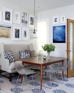 a living room with pictures on the wall and a table in front of some chairs