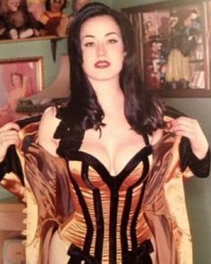 a woman is wearing a corset and posing for the camera in her bedroom