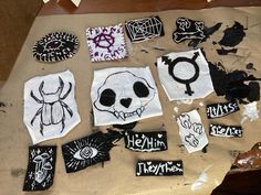 various patches and stickers on a table with some type of artwork in the background