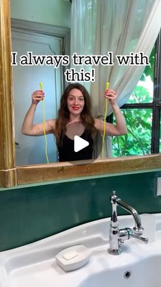 a woman standing in front of a bathroom mirror holding two hairdryers over her head