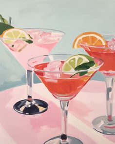 two martinis with lemon slices and garnishes on a pink tablecloth