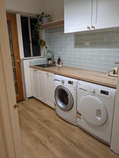 a washer and dryer sitting in a kitchen next to each other on top of a hard wood floor