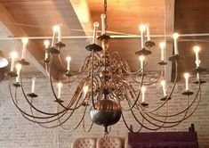 a chandelier hanging from the ceiling in a room with brick walls and exposed ceilings