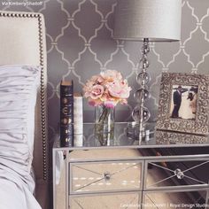 a bedroom with a bed, nightstand and flowers on top of the night stand in front of it