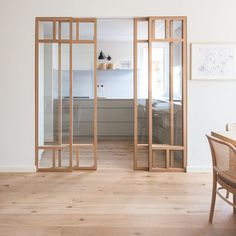 an open room with wooden floors and white walls, has glass doors that lead into the bedroom