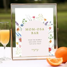 there is a glass of orange juice next to an orange slice and a sign that says mom - osa bar