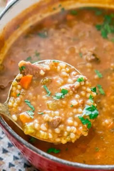 a ladle full of soup is being held by a spoon