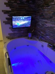 a large jacuzzi tub sitting in front of a tv mounted on the wall