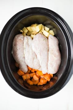 chicken, potatoes and carrots in a crock pot on a white table top