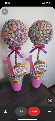 two pink buckets filled with candy lollipops on top of a table