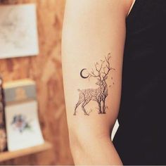 a woman's arm with a deer tattoo on it, and the moon in the background