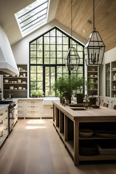 an open kitchen with lots of counter space and hanging lights above the island, in front of a large window