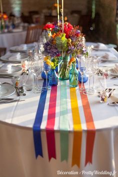 the table is set with colorful flowers and wine glasses