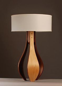 a wooden table lamp with a white shade on the top and bottom part of it