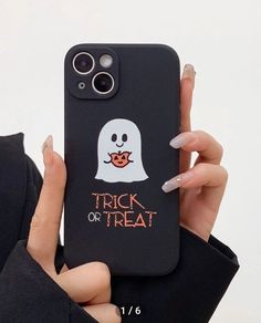 a woman holding up a phone case with a ghost on it and trick or treat written on the back