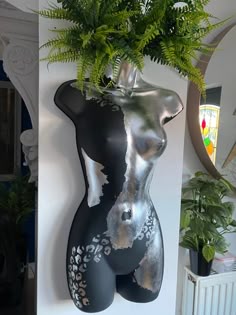 there is a plant in the shape of a woman's body on display next to a mirror