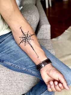 a man with a compass tattoo on his arm