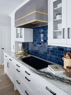 a kitchen with white cabinets and blue tile on the backsplash is pictured in this image