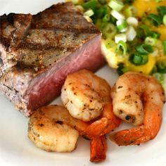 a white plate topped with meat, shrimp and vegetables