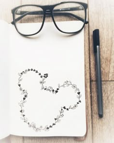 an open notebook with a heart drawn on it next to a pen and eyeglasses