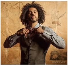 a man with curly hair is adjusting his tie