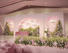 the stage is decorated with pink flowers and greenery for a wedding ceremony or reception